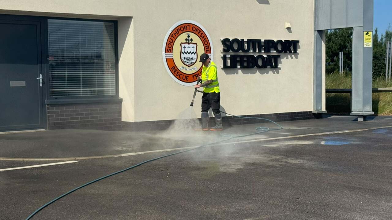 Hot water pressure washing a commercial forecourt, steam rising