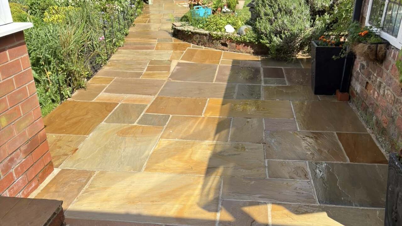 A natural stone patio and garden path after cleaning, in sunshine