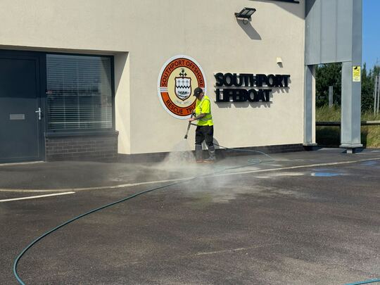 Pressure washing a commercial forecourt with hot water, steam rising