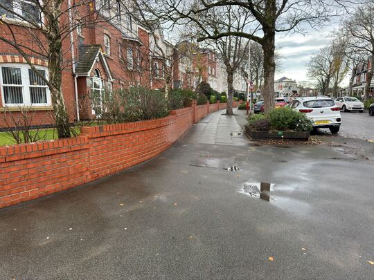 Clean communal path and red brick wall alongside a block of flats