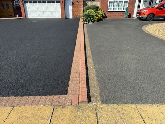 Two neighbouring tarmac driveways, one freshly cleaned and darker, the other faded