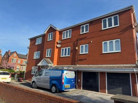 Three-storey red brick block of flats with the Pinnacle NW van parked outside and the SkyVac Interceptor set up by the entrance