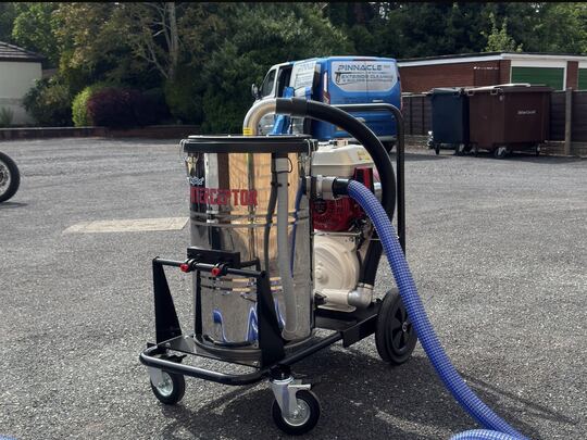 Stainless steel SkyVac Interceptor on wheels with a blue hose