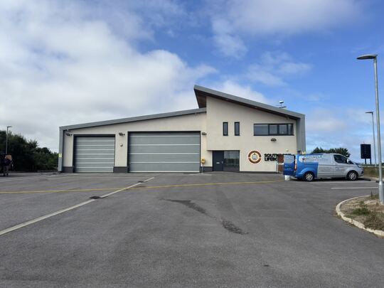 A white rendered lifeboat station with the Pinnacle NW van parked outside during a render clean